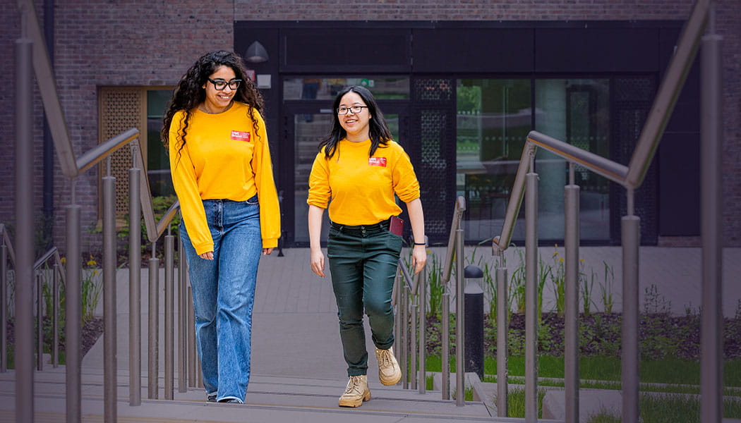 Two students in UWE Bristol sweatshirts walking up some steps