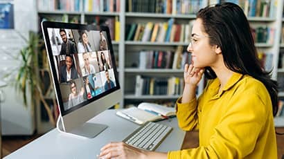 A young woman attending a group video call using a computer.