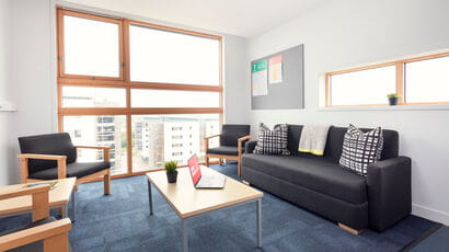 A typical communal area in the Student Village with sofas and a coffee table in front of a large window.