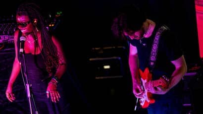 A black woman singing and a white man playing guitar on stage.