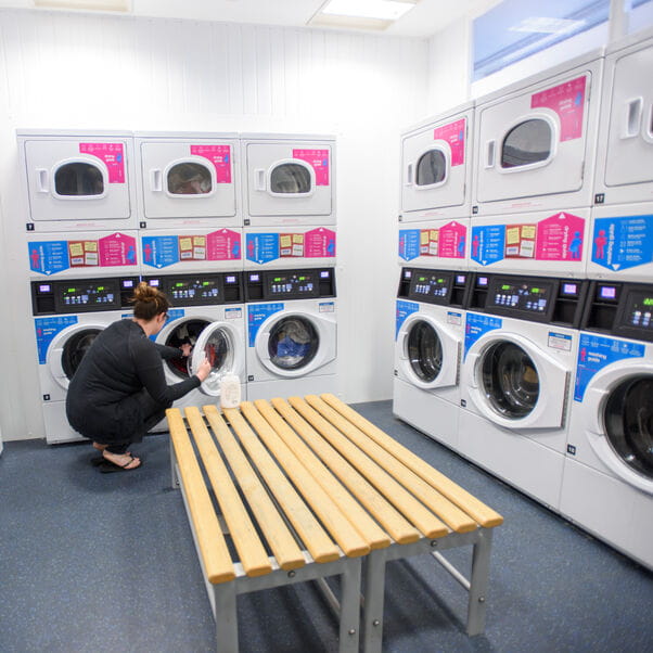 A student in the laundry room doing a load of washing.