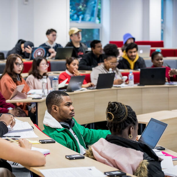 A lecture hall filled with students listening to the programme leader.