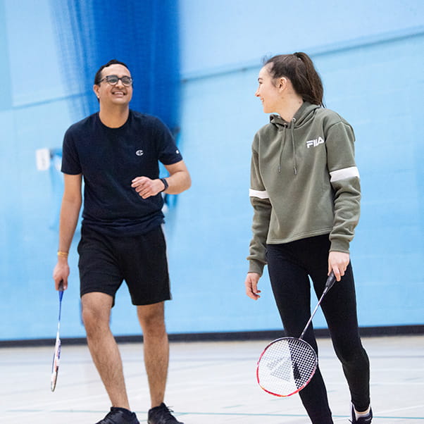 Man and women chatting during a game of badminton.