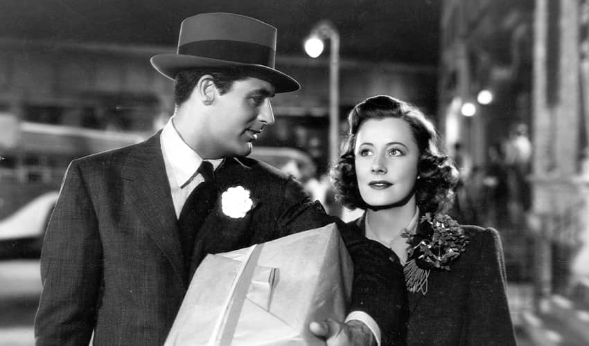 Two people walking at night, one holding a large paper-wrapped package.