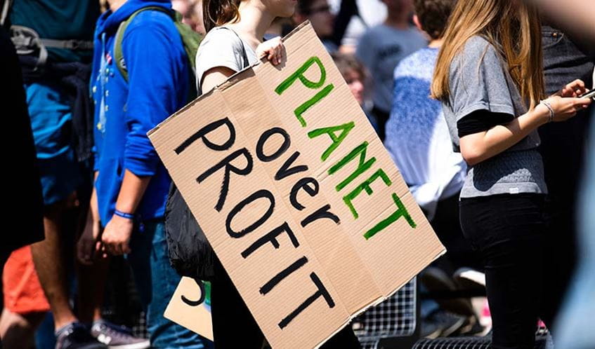 Person holding a 'Planet over profit' placard