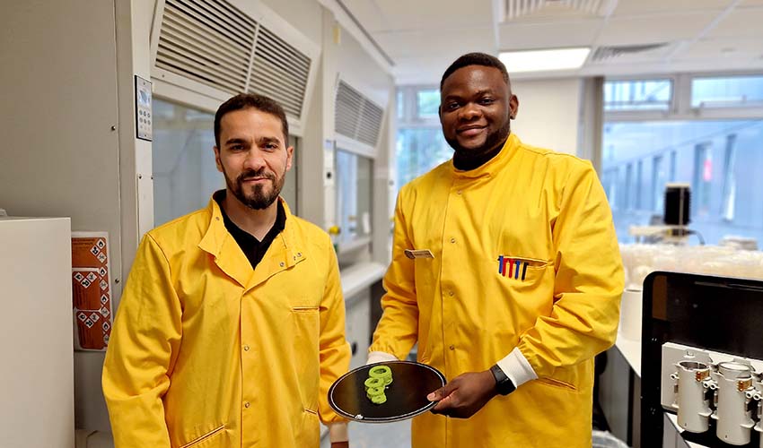 Two male researchers in yellow lab coats holding up a plate of 3D printed food