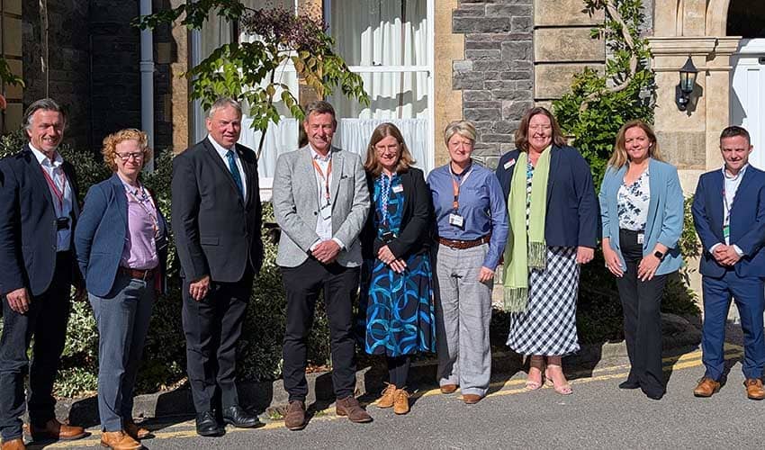 A group of people smiling at the camera while standing outside a historic building