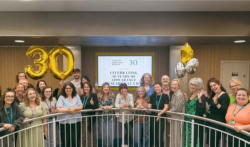 Members of the Centre for Appearance Research standing for a group photo, with balloons in the background