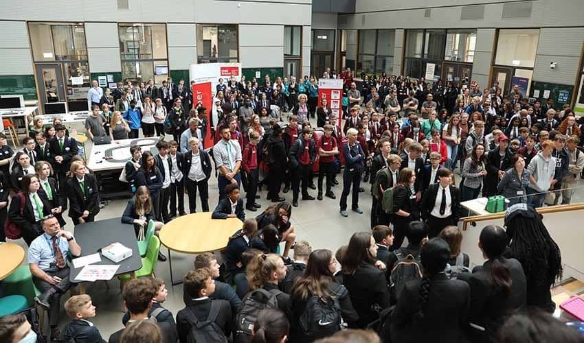 A wide angled photograph showing dozens of children and adults attending a large cyber security careers event