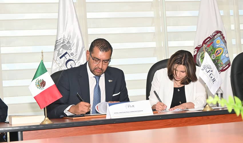 Two people signing documents while sat a desk