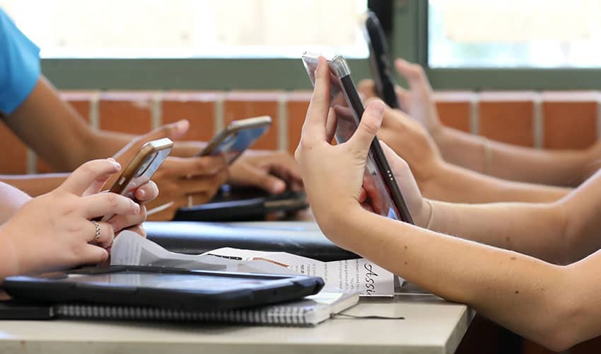 Image showing the hands of four school pupils using their smartphones
