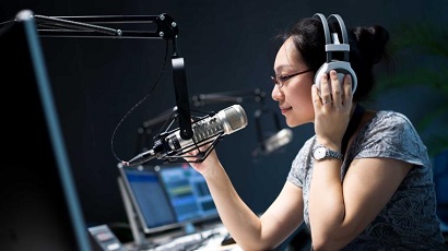 A student speaking into a microphone in a radio studio