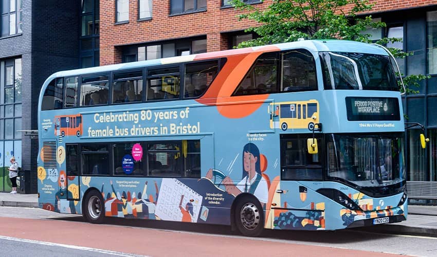 A double-decker bus is covered in an illustration celebrating women bus-drivers