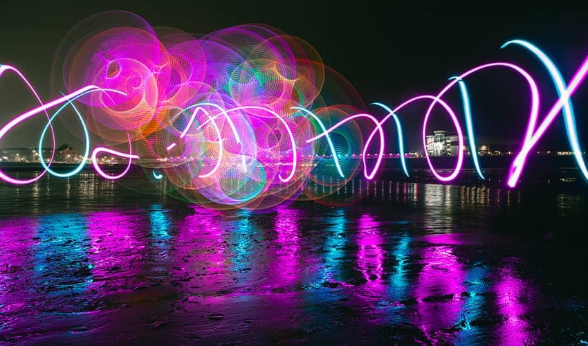 A colourful display of twirling lights above water.