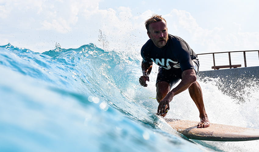 A man in a black rash vest riding a surfboard 