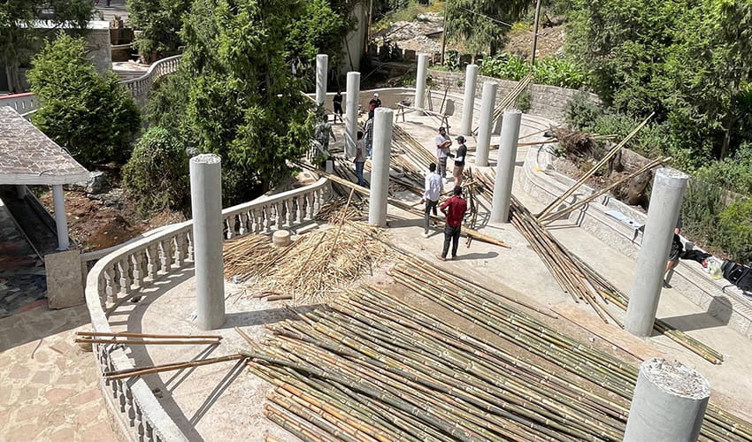 A pavilion space with hundreds of large pieces of bamboo stacked in the middle of the space 