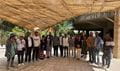 A large group of people stood underneath a bamboo structure 