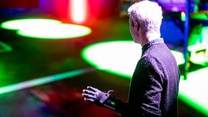 A man using a immersive experience glove in a room filled with bright lights