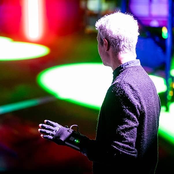 A man using an extended reality glove in a performance space.