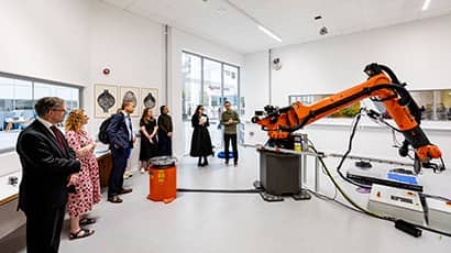 A group of people looking at a large robotic arm in a laboratory