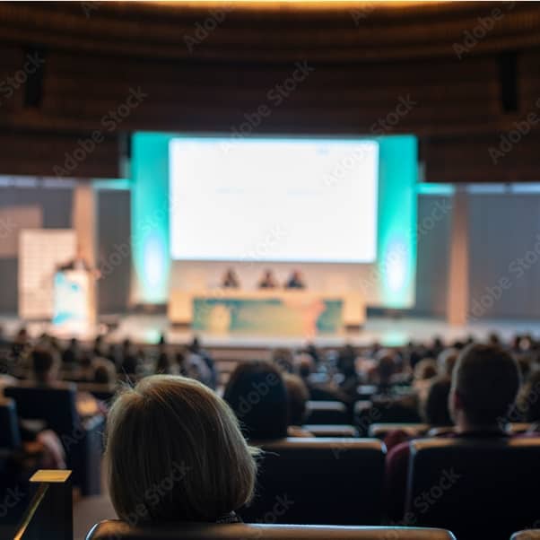 Rear view shot of an audience over the speakers on the stage in a conference hall.