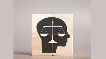 Four wooden cubes stacked together in a square formation to show the scales of justice within a head profile outline.