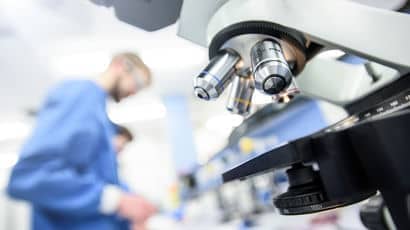 Researchers in a lab with a microscope