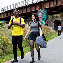 Two students in summer clothes walking along a footpath in Bristol.