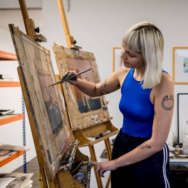 Artist painting on an easel in a studio.