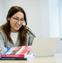 A student sits at a table working on a laptop.