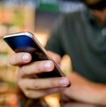 Close up of a seated man typing on a smart phone