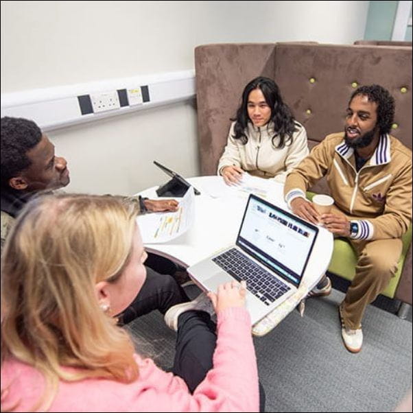 A group of students studying together with a laptop.